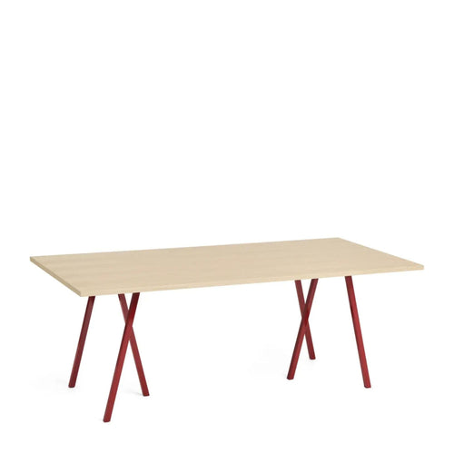 A rectangular table with a light wood tabletop and red metallic legs.